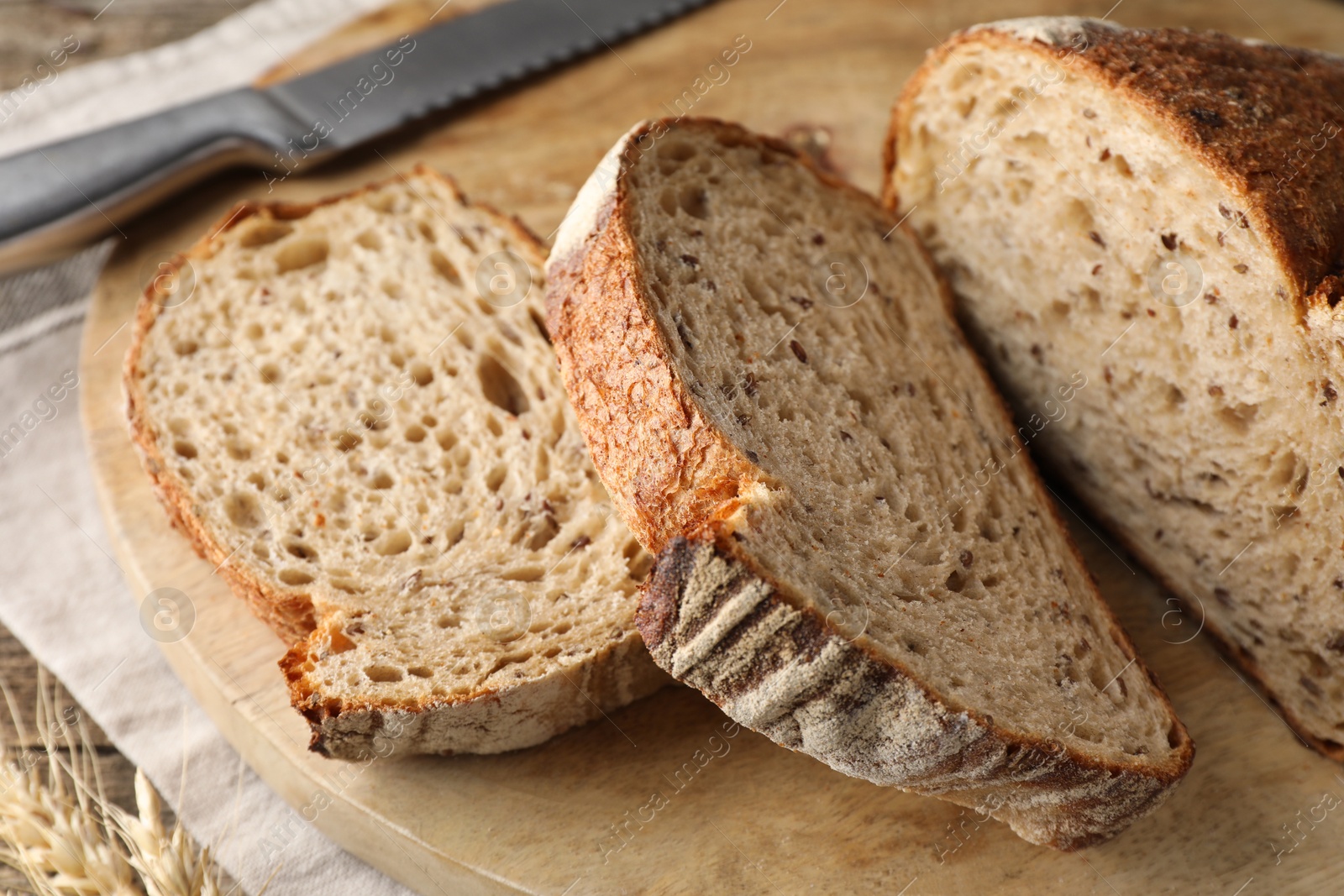 Photo of Cut loaf of fresh bread and knife on wooden table, closeup