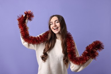 Photo of Happy young woman with tinsel on purple background