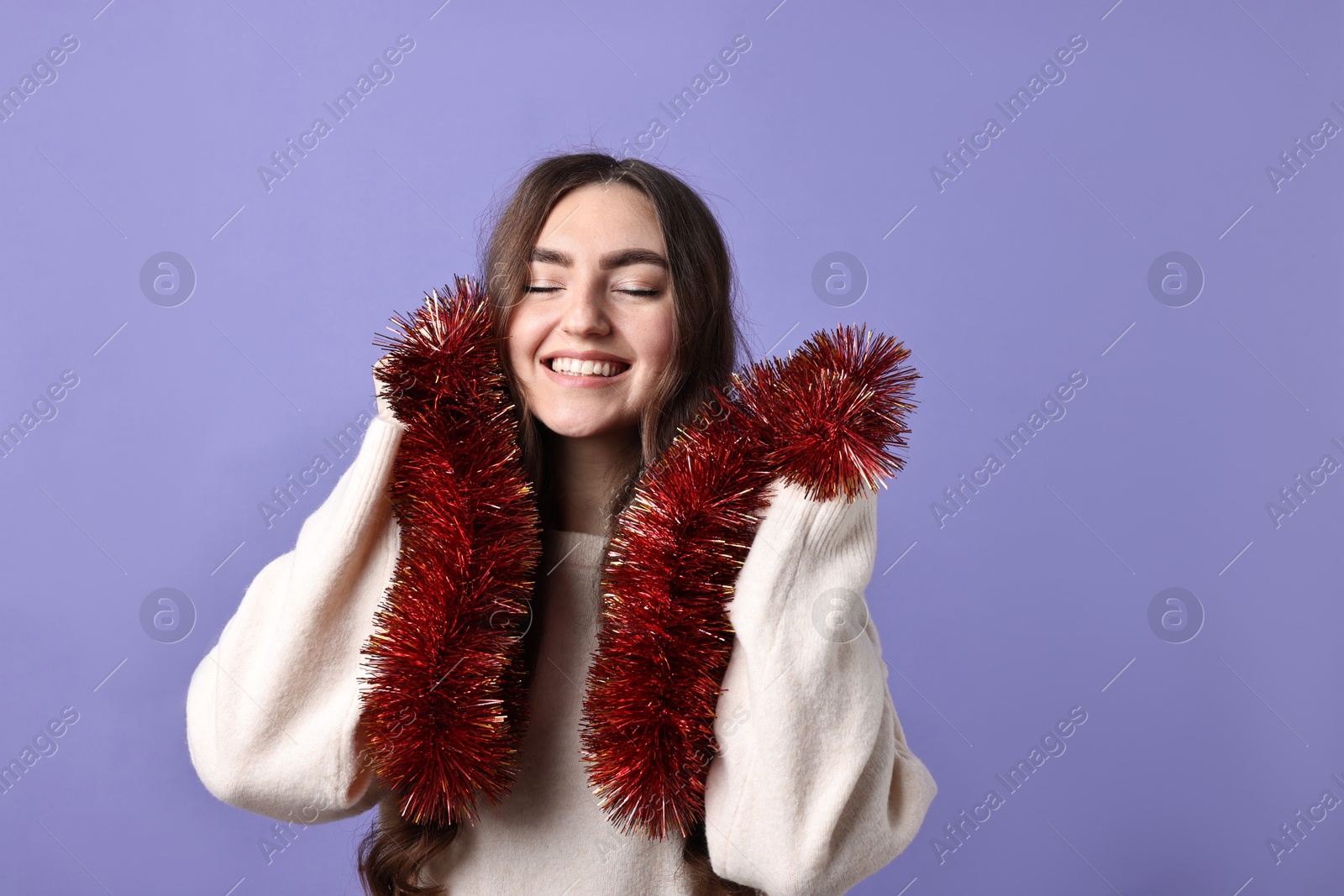 Photo of Happy young woman with tinsel on purple background