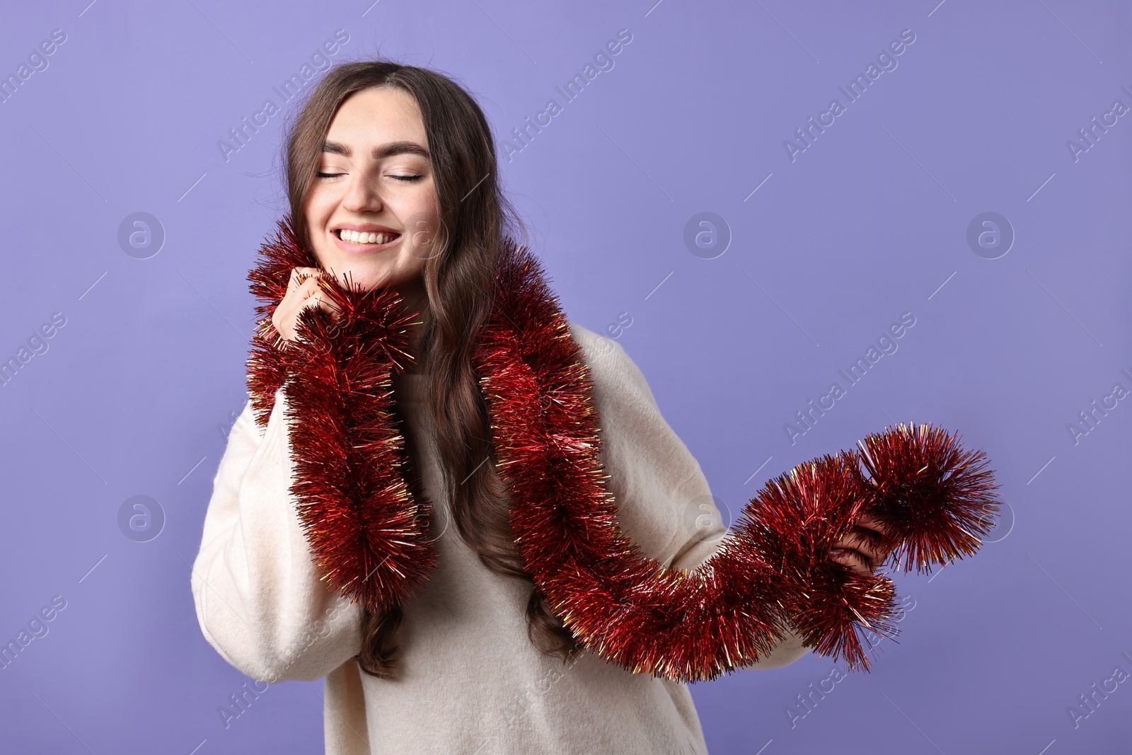 Photo of Happy young woman with tinsel on purple background