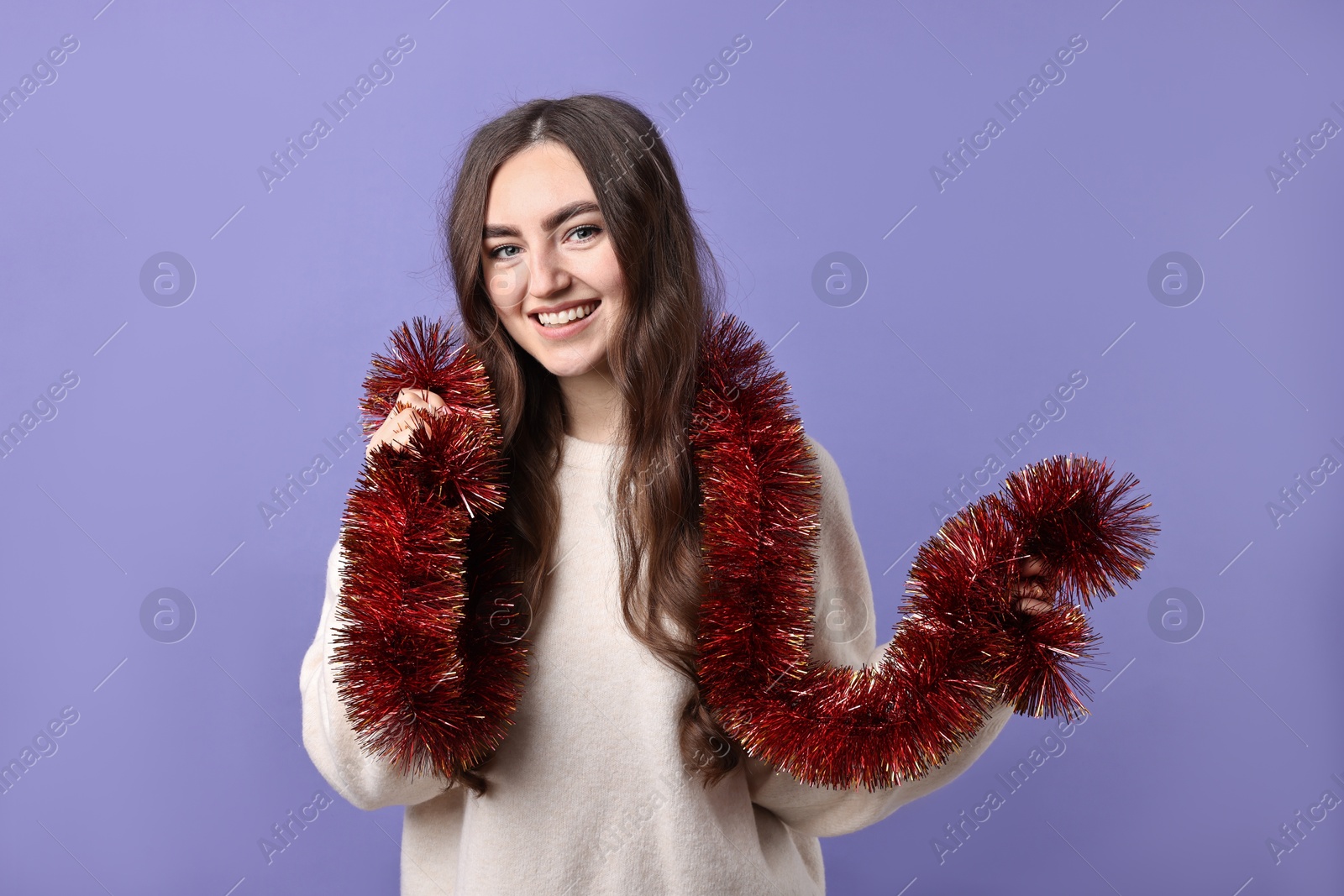 Photo of Happy young woman with tinsel on purple background