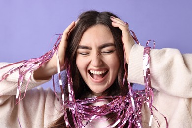 Photo of Excited young woman with bright tinsel on purple background