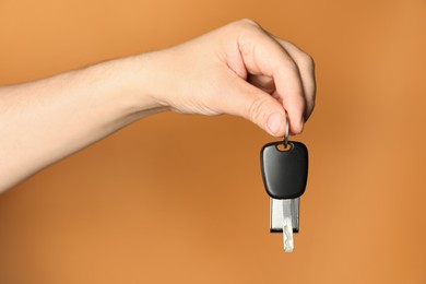 Photo of Man with car key and keychain on orange background, closeup