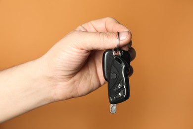 Photo of Man with car keys on orange background, closeup