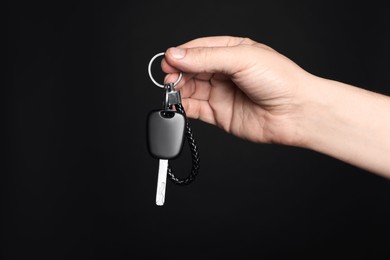 Photo of Man with car key and keychain on black background, closeup. Space for text