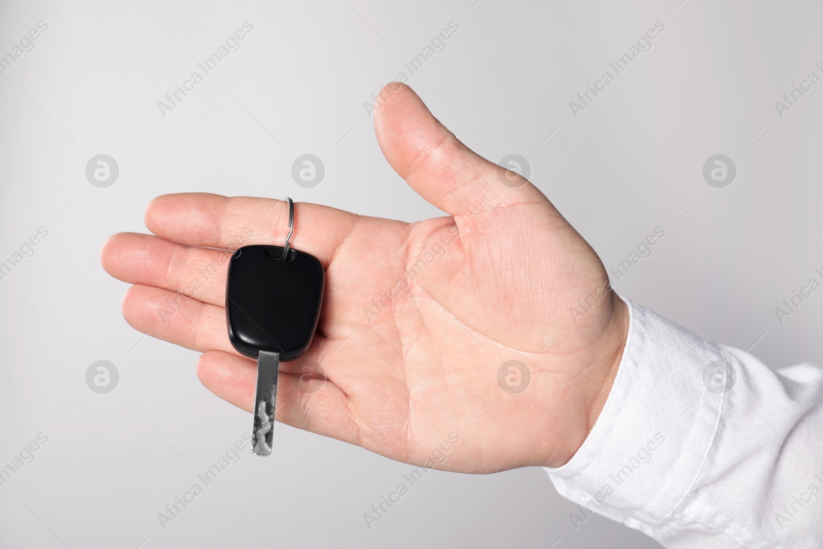 Photo of Man with car key on light grey background, closeup