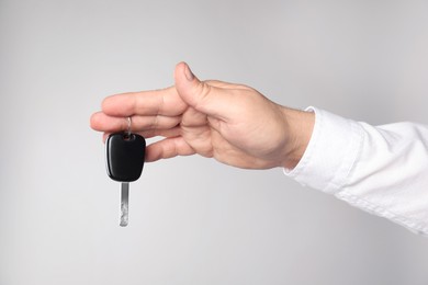 Photo of Man with car key on light grey background, closeup