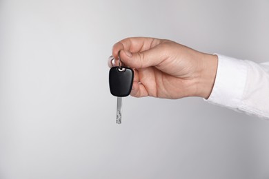 Photo of Man with car key on light grey background, closeup. Space for text