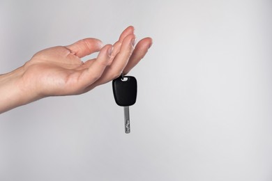 Man with car key on light grey background, closeup. Space for text