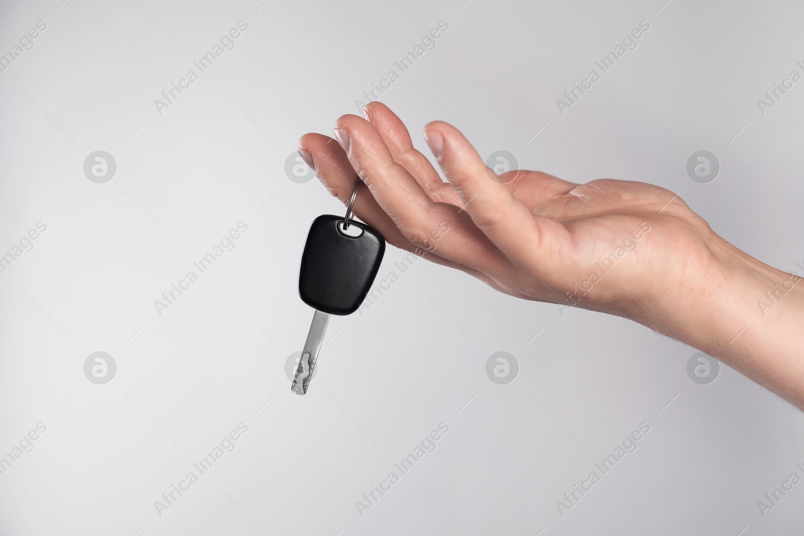 Photo of Man with car key on light grey background, closeup. Space for text