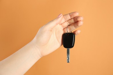 Photo of Woman with car key on orange background, closeup