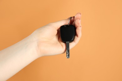 Photo of Woman with car key on orange background, closeup