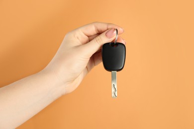 Photo of Woman with car key on orange background, closeup