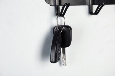 Car keys on hanger against grey wall, closeup