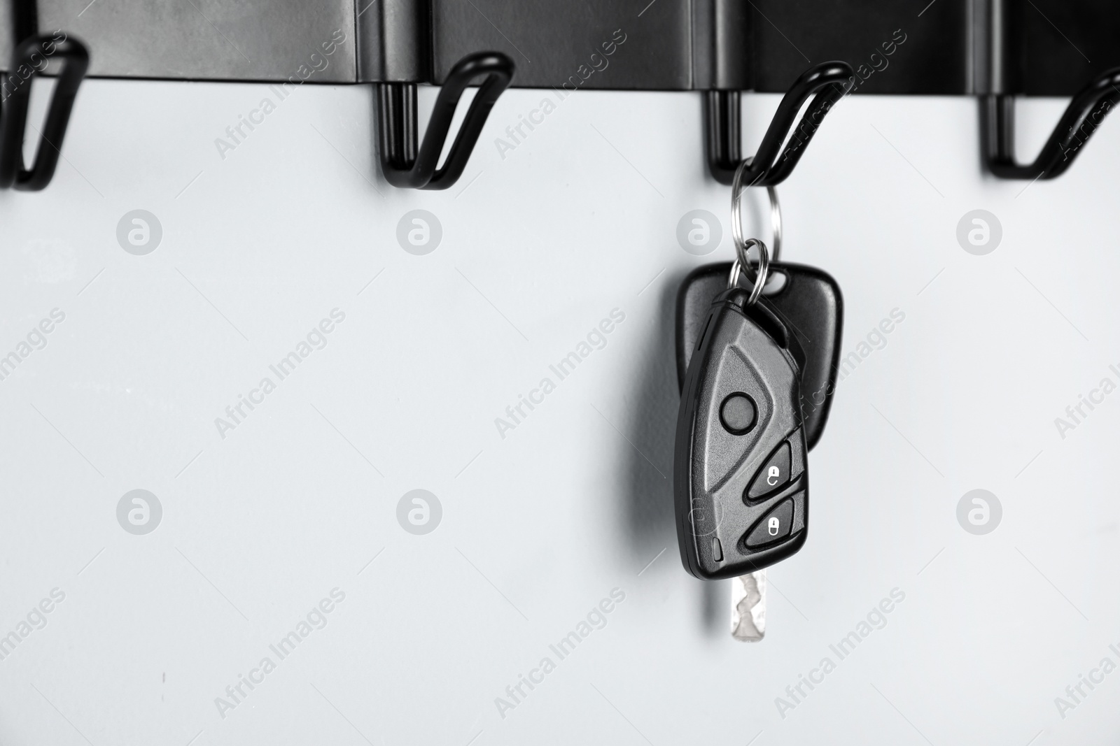 Photo of Car keys on hanger against light wall, closeup