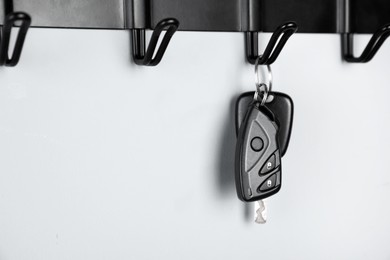 Car keys on hanger against light wall, closeup