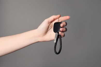 Photo of Woman with car key and keychain on grey background, closeup