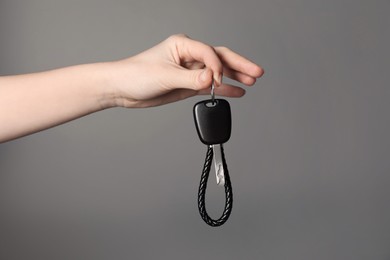 Photo of Woman with car key and keychain on grey background, closeup