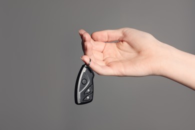 Photo of Woman with car flip key on grey background, closeup. Space for text