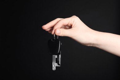 Photo of Woman with car key and keychain on black background, closeup. Space for text