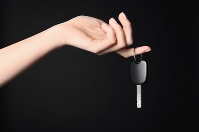 Woman with car key on black background, closeup