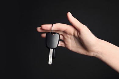 Woman with car key on black background, closeup