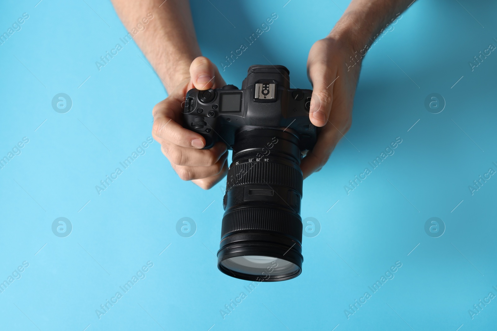 Photo of Photographer with professional camera on light blue background, above view