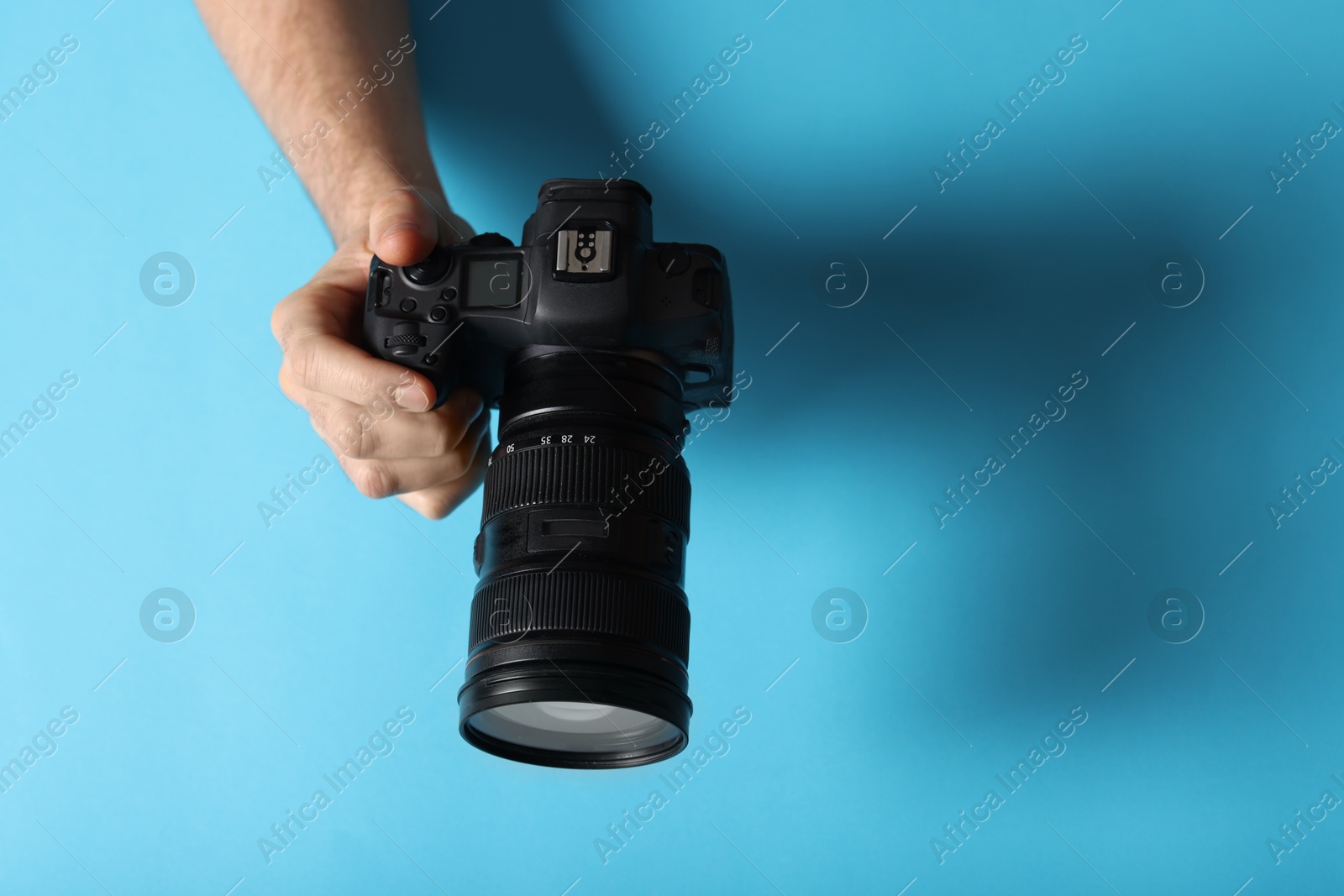 Photo of Photographer with professional camera on light blue background, above view. Space for text