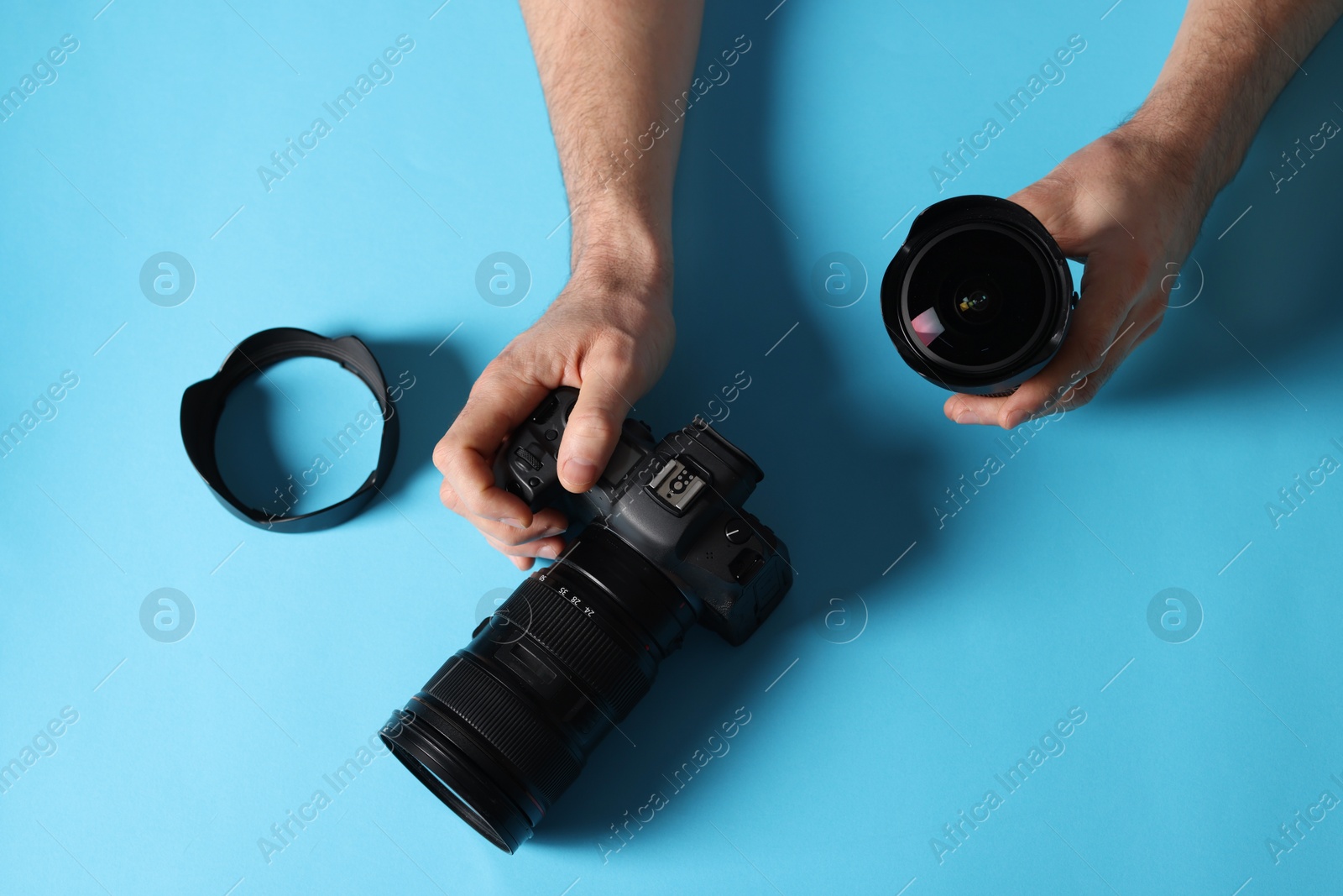 Photo of Photographer with professional camera and equipment on light blue background, top view