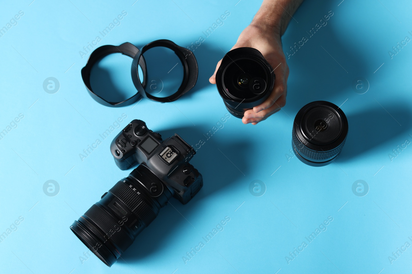 Photo of Photographer with professional camera and equipment on light blue background, top view