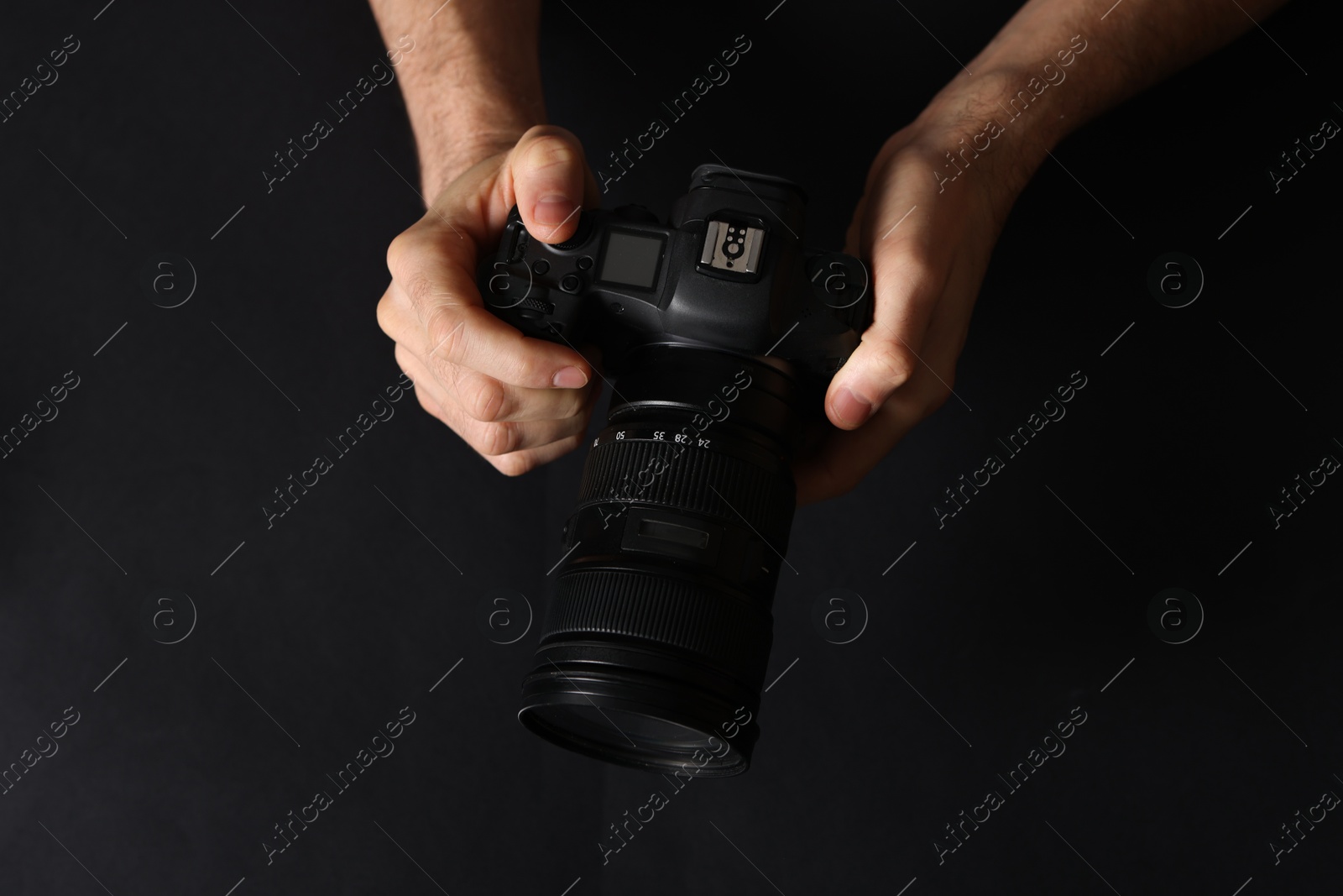 Photo of Photographer with professional camera on black background, top view