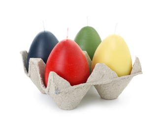 Photo of Colorful egg-shaped candles in carton isolated on white. Easter decor