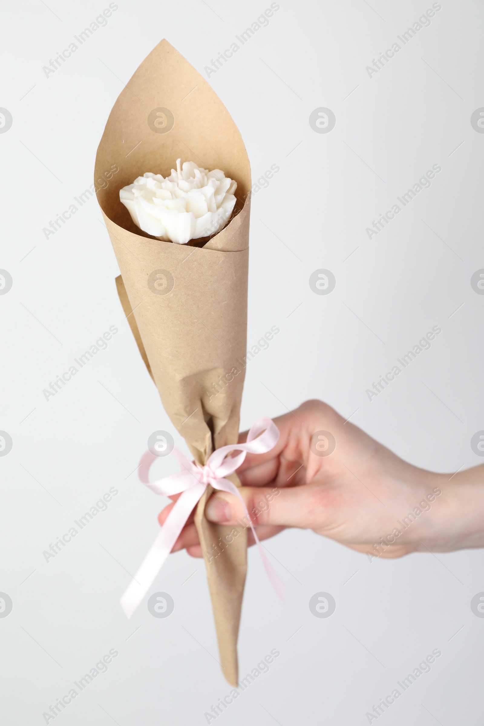 Photo of Woman with beautiful flower shaped candle on white background, closeup