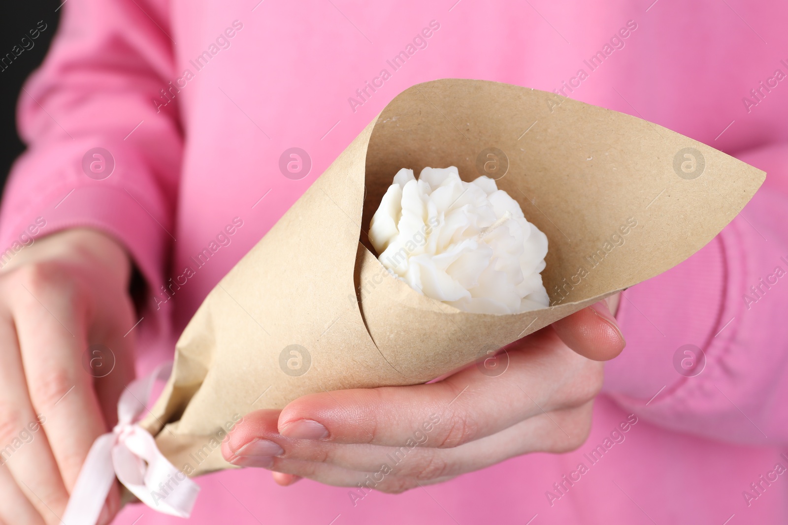 Photo of Woman with beautiful flower shaped candle on black background, closeup