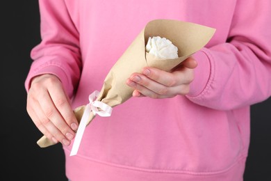 Photo of Woman with beautiful flower shaped candle on black background, closeup