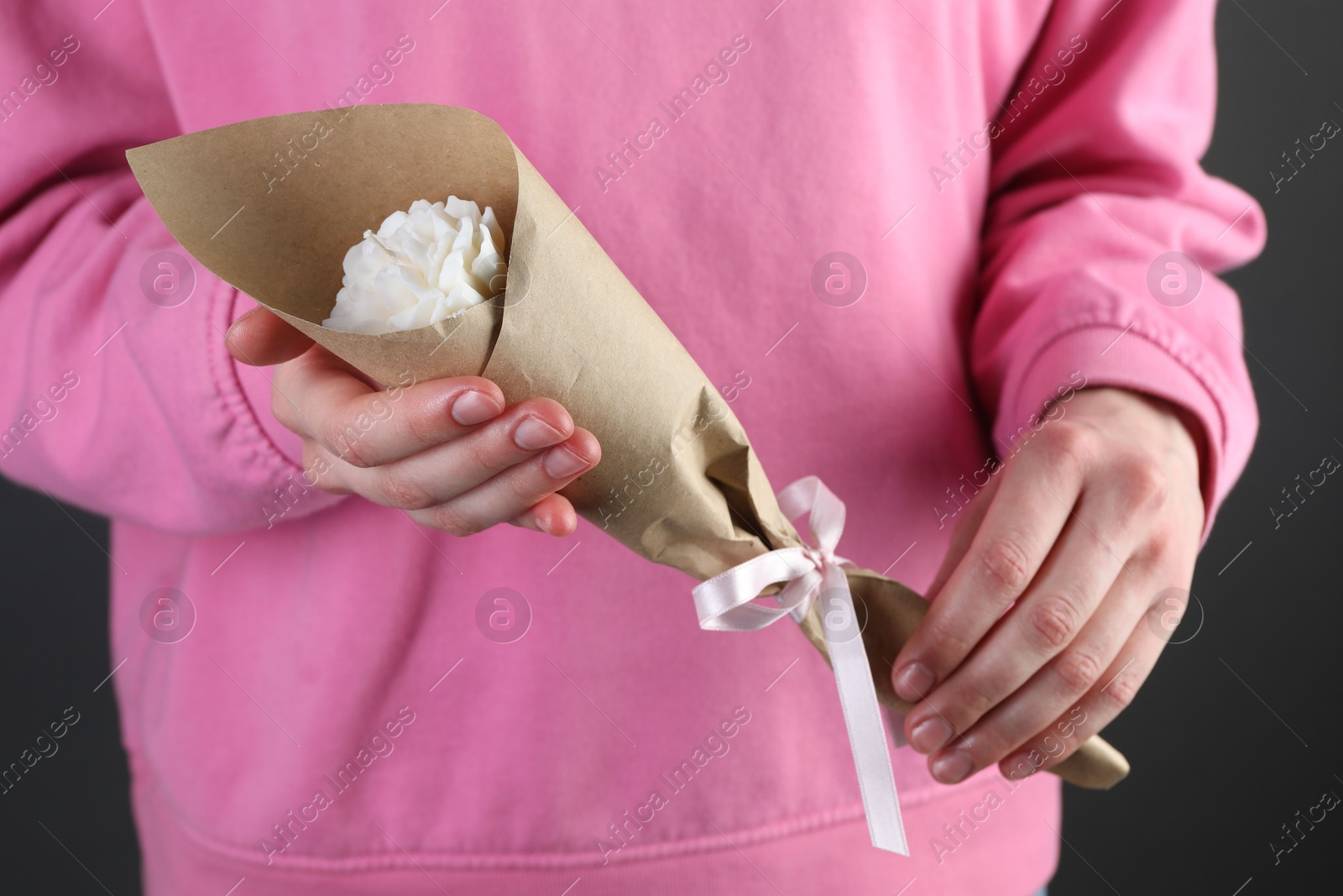 Photo of Woman with beautiful flower shaped candle on black background, closeup