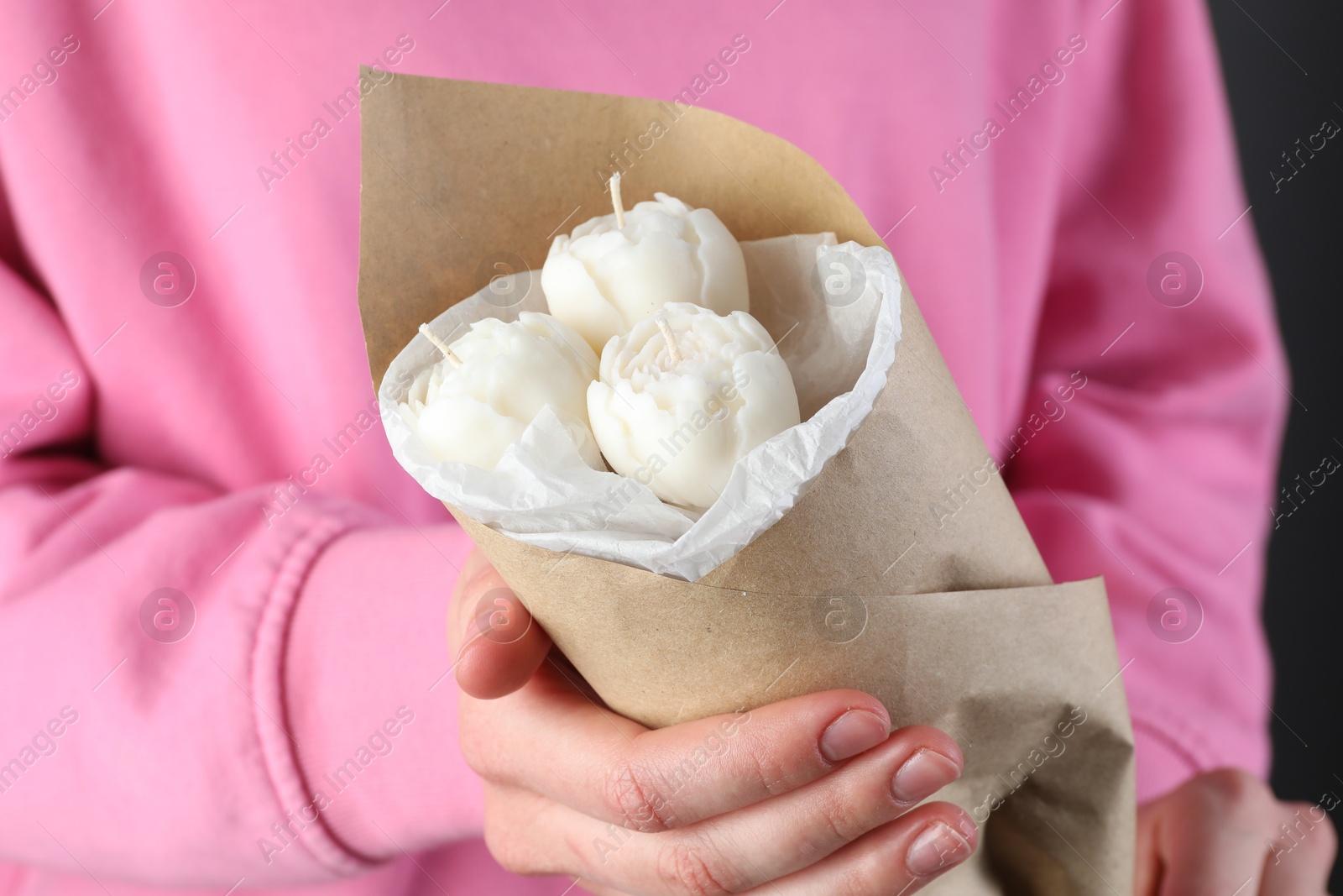 Photo of Woman with bouquet of beautiful flower shaped candles on black background, closeup