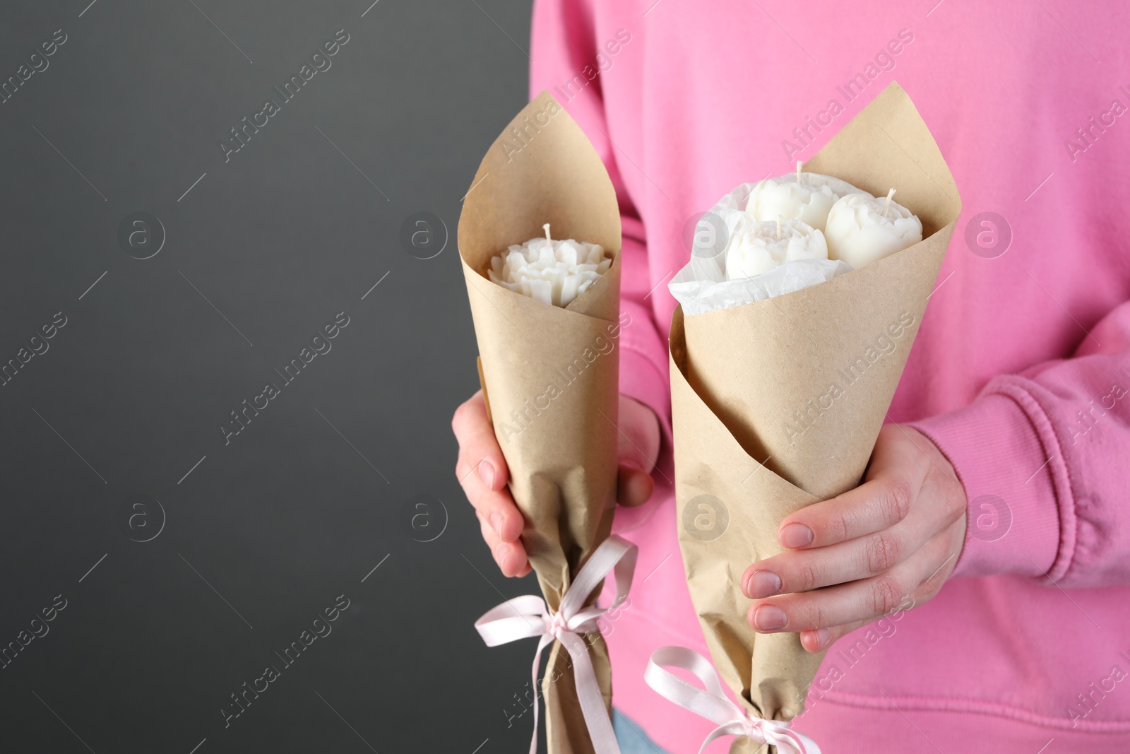 Photo of Woman with beautiful flower shaped candles on black background, closeup. Space for text