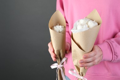 Photo of Woman with beautiful flower shaped candles on black background, closeup. Space for text