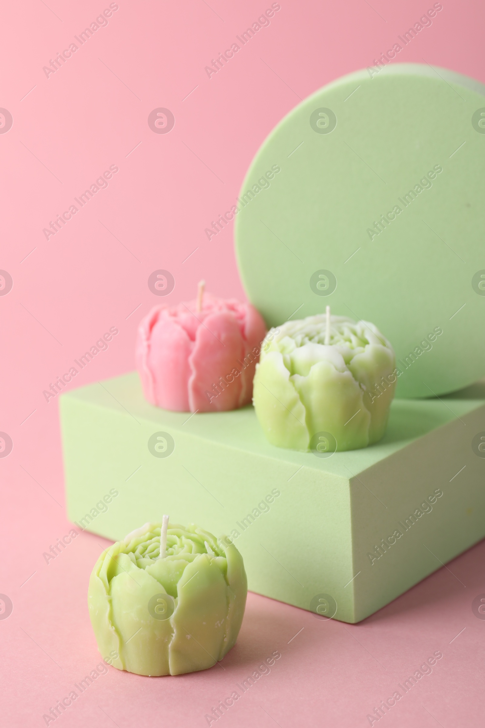 Photo of Beautiful flower shaped candles on pink background