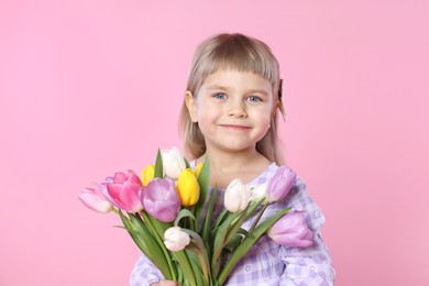 Photo of Cute little girl with bouquet of tulips on pink background