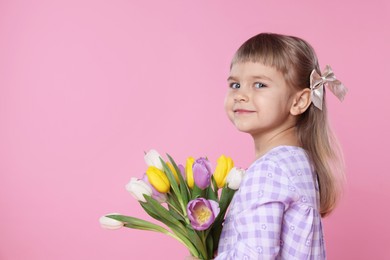 Photo of Cute little girl with bouquet of tulips on pink background. Space for text