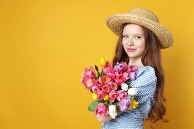 Photo of Beautiful teenage girl with bouquet of tulips on orange background, space for text