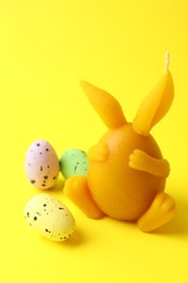 Photo of Beautiful candle and candies on yellow background, closeup. Easter decor