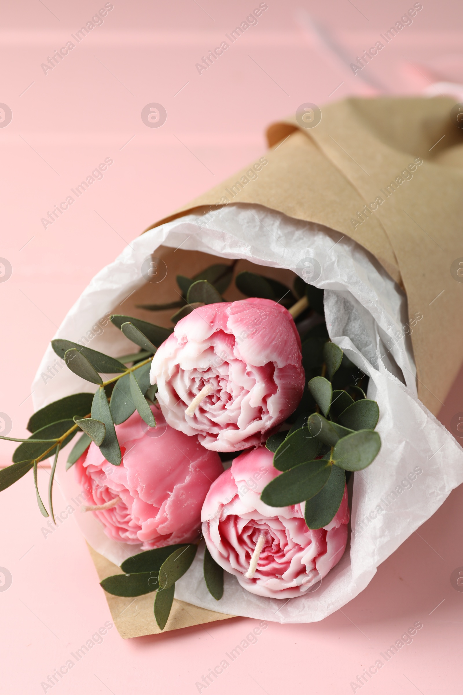 Photo of Beautiful bouquet of flower shaped candles on pink wooden background, closeup