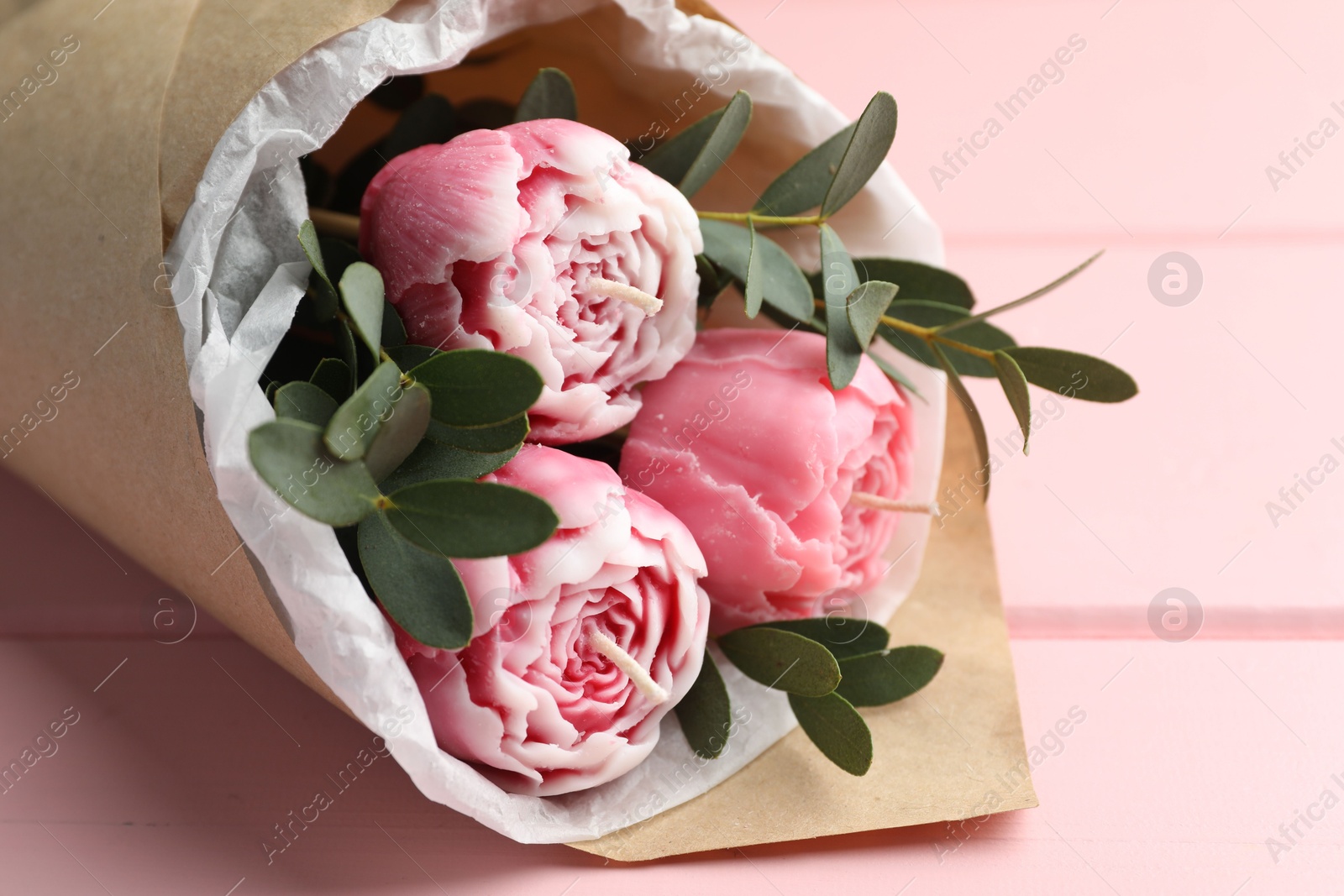 Photo of Beautiful bouquet of flower shaped candles on pink wooden background, closeup