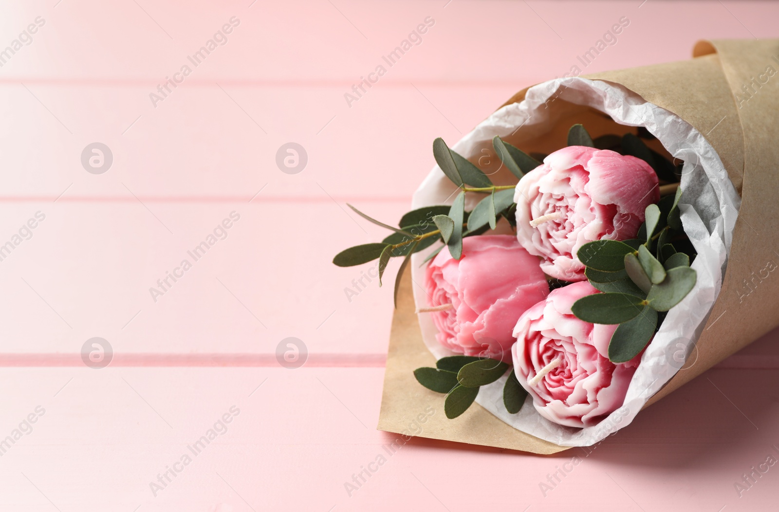 Photo of Beautiful bouquet of flower shaped candles on pink wooden background, closeup. Space for text