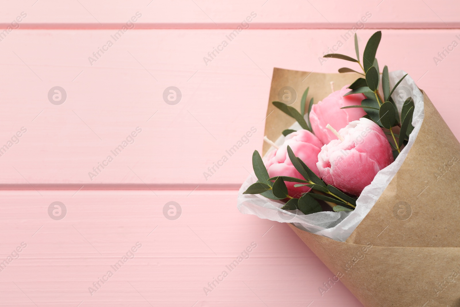 Photo of Beautiful bouquet of flower shaped candles on pink wooden background, top view. Space for text