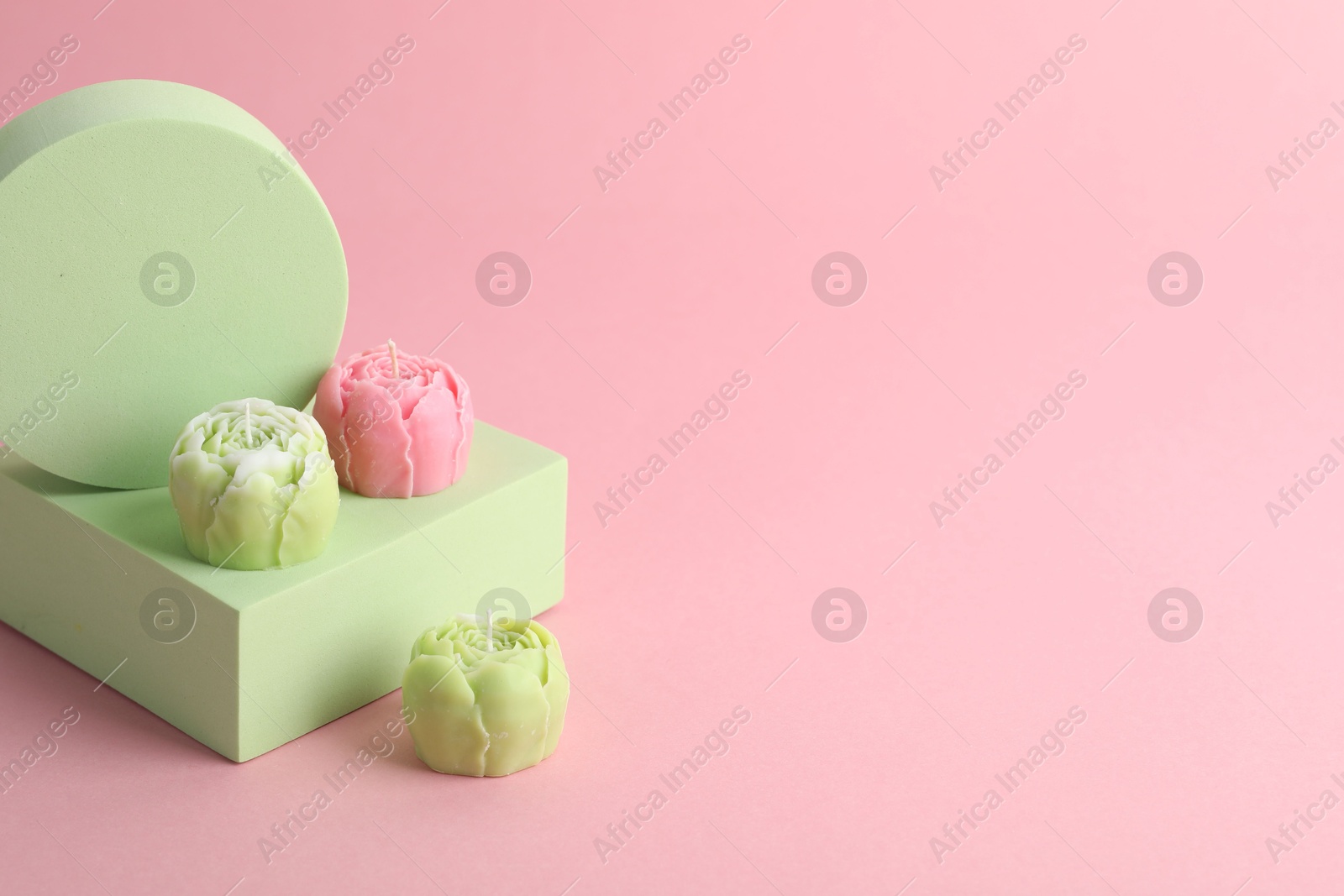 Photo of Beautiful flower shaped candles on pink background. Space for text