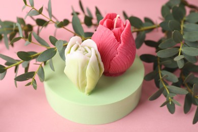 Photo of Beautiful flower shaped candles and leaves on pink background, closeup